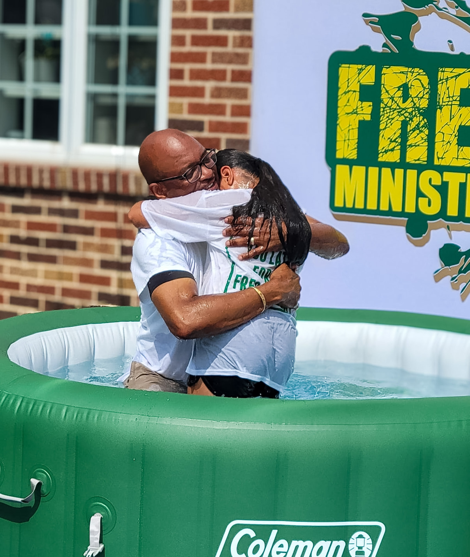 A joyful embrace after an outdoor water baptism
